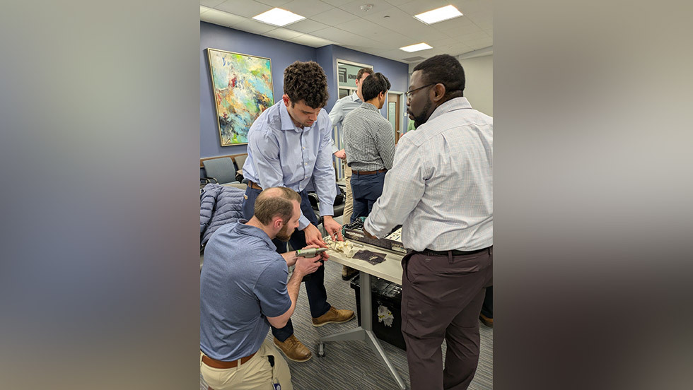 people using a drill on a bone model