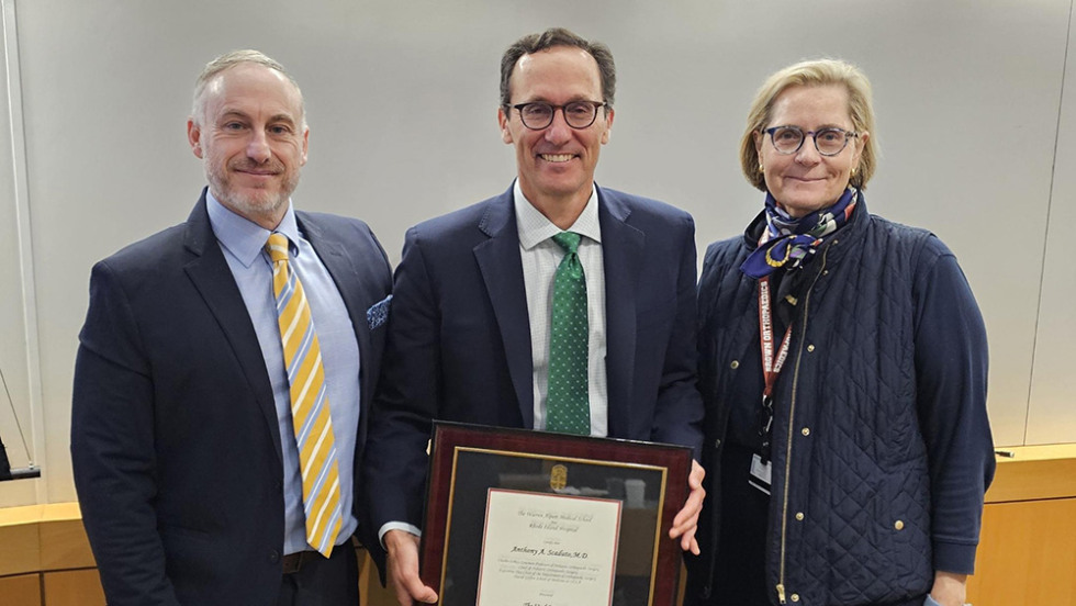 three people posing with an award