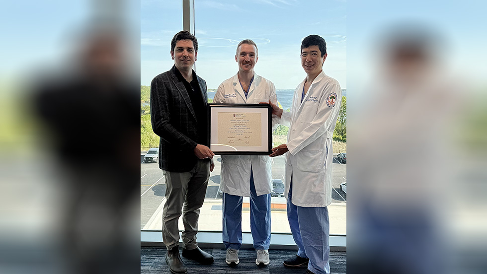 three people posing with a framed document